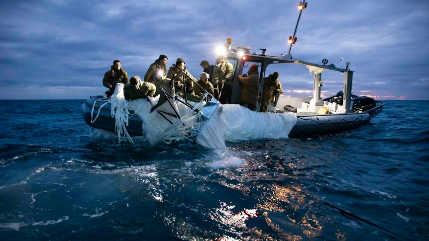 A g一群人在船上拉着一块大塑料布